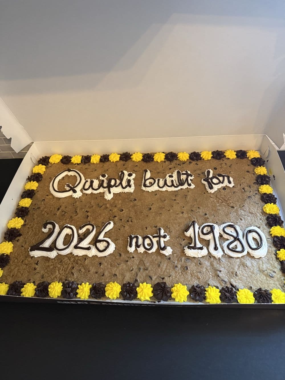 A Quipli cookie cake that reads "Quipli built for 2026 not 1980"