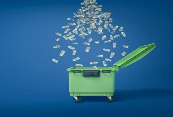 Money raining down in green dumpster.